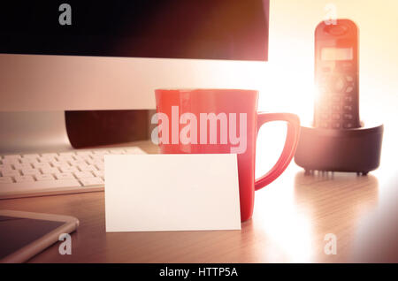 Table de bureau avec ordinateur, smartphone, téléphone de bureau, tasse de café et blank business card. Concept pour contact site web page et banner, imprimé m Banque D'Images