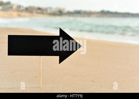 Libre d'une pancarte vide noir dans la forme d'une flèche sur le sable d'une plage Banque D'Images