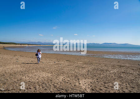 Femme à l'aide d'un téléphone mobile sur une plage déserte sur l'île Llanddwyn (Ynys Llanddwyn). Anglesey au nord du Pays de Galles. Banque D'Images