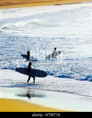 Pour les surfeurs surf dans l'océan au coucher du soleil Banque D'Images