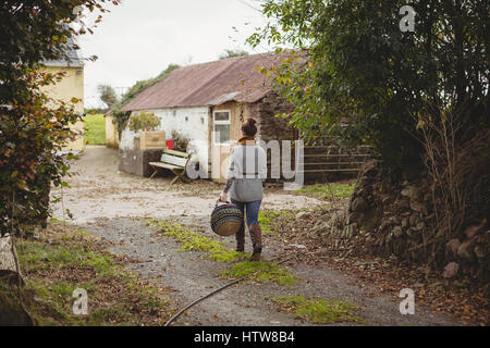 Femme avec panier walking on road in field Banque D'Images