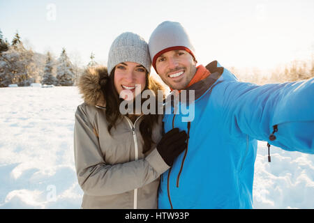 Couple heureux de prendre un paysage de neige sur selfies Banque D'Images