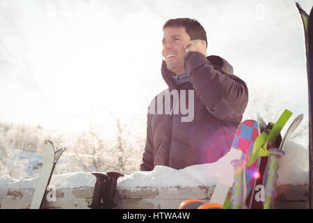 L'homme dans des vêtements d'hiver à parler au téléphone contre la lumière du soleil Banque D'Images