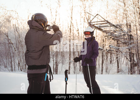 Man photographing woman skieur dans station de ski Banque D'Images