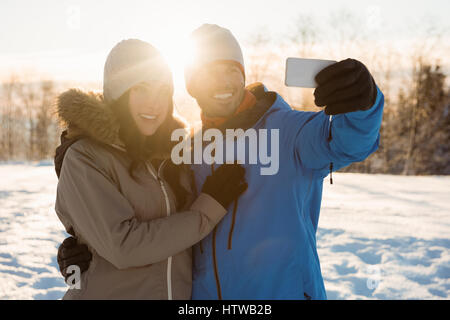 Couple heureux de prendre un paysage de neige sur selfies Banque D'Images