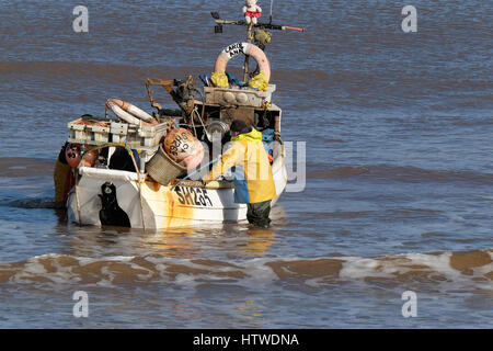 Shell petit bateau de pêche avec deux hommes d'équipage de retourner à la plage à Hornsea dans le Yorkshire, UK. Banque D'Images