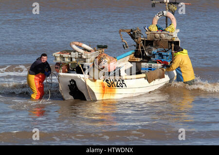 Shell petit bateau de pêche avec deux hommes d'équipage de retourner à la plage à Hornsea dans le Yorkshire, UK. Banque D'Images