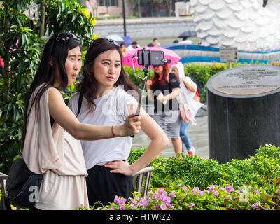 Deux jeunes femmes de Singapour de prendre une photo en selfies Marina Bay, Singapour. Banque D'Images