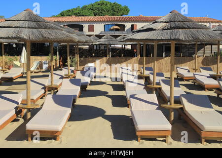 Transats en bois avec que des parasols sur le sable en face d'un restaurant de plage Banque D'Images