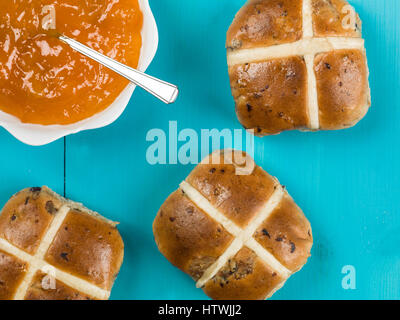 Hot cross bun avec confiture d'abricot sur un fond bleu Banque D'Images
