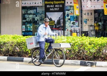 Singapour Postman postman circonscription une bicyclette. Banque D'Images