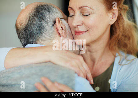 Portrait de senior personnes embrassant heureusement, woman hugging old grey haired man smiling caringly avec joie et fermant les yeux Banque D'Images