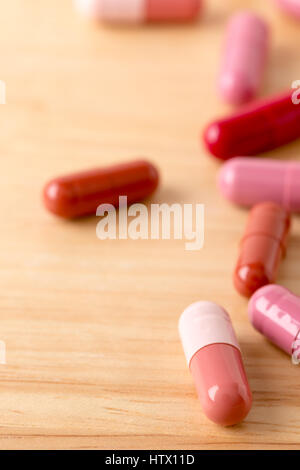 Dispersés capsules de couleur rouge et brun sur la table en bois Banque D'Images