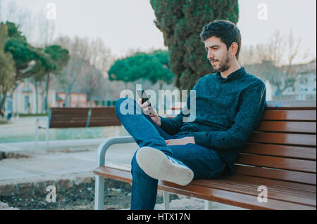 Jeune mexicaine homme assis dans un banc dans un parc Banque D'Images