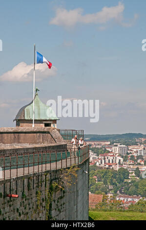 Drapeau tricolore français volant au-dessus d'une tour sur les remparts de la Citadelle de Besançon fort, en France. Deux personnes sont en ordre décroissant les marches de la tour Banque D'Images