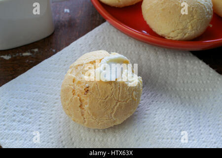 Gros plan sur la bouche-arrosage pain fromage brésilien (Pao de Queijo) garni de beurre à une serviette en papier blanc, et un groupe de pains dans l'arrière-plan sur Banque D'Images