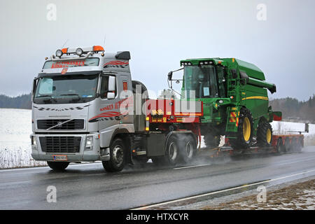 SALO, FINLANDE - le 10 mars 2017 : Volvo FH16 560 John Deere semi parcours W440 combine harvester sur remorque col de cygne le long de la route humide, des pluies en début de spr Banque D'Images