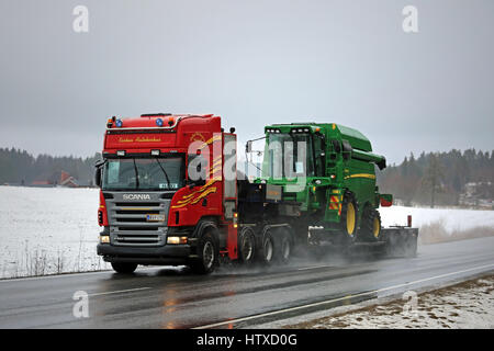 SALO, FINLANDE - le 10 mars 2017 : Scania R560 John Deere semi distances W440 moissonneuse batteuse sur route humide le long de la remorque de cygne sur le début du printemps pluvieux wea Banque D'Images