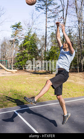 Jeune homme musclé fit sauter lancer en basket-ball hoop Banque D'Images