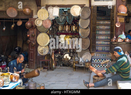 Fes, Maroc. Place Seffarine. Les métallurgistes façonner un bol de cuivre et un vase en métal. Banque D'Images