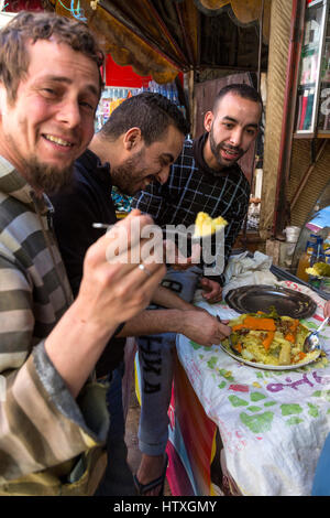 Fes, Maroc. Trois jeunes hommes partageant un repas dans la vieille ville. Banque D'Images