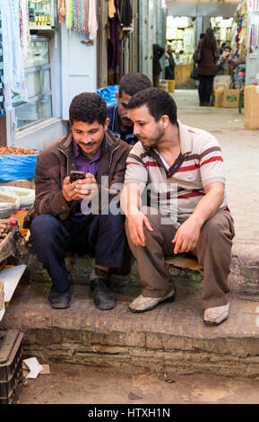 Fes, Maroc. Les jeunes hommes contrôler un téléphone cellulaire dans la médina. Banque D'Images