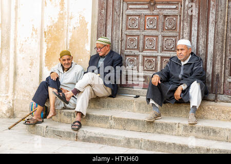 Fes, Maroc. Trois hommes âgés se reposant sur les marches de la mosquée andalouse, Fès El-Bali. Banque D'Images