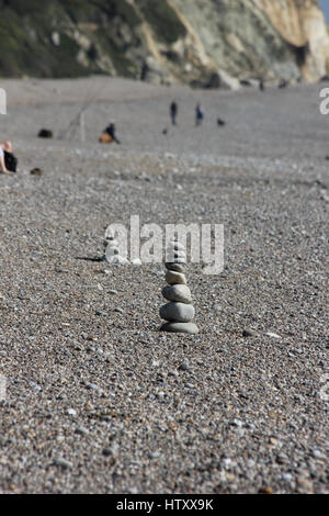 Un cairn de pierres disposées sur la plage de Branscombe, Devon, avec un autre cairn de cailloux disposés derrière un jour ensoleillé Banque D'Images