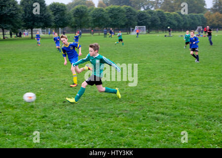 Les garçons jouent au football (soccer) dans un parc le samedi matin Grande-bretagne UK KATHY DEWITT Banque D'Images