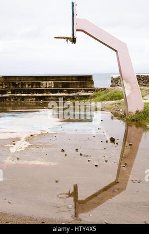 Un terrain de basket-ball et le soutien net du bras de béton se reflétant dans les eaux de la cour inondée. Banque D'Images