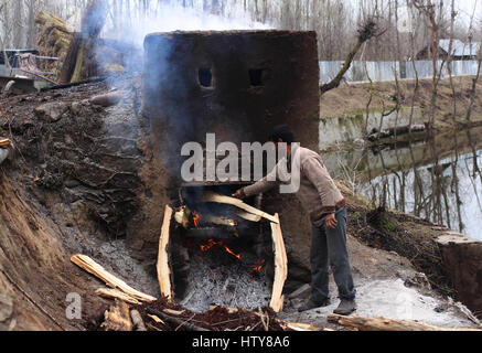 Srinagar, Inde. Mar 15, 2017. * Un jeune homme Cachemire met le feu-bois dans un petit four pour chauffage wickers pour peler facilement.le Mercredi, Mars 15, 2017, dans la banlieue de Srinagar, dans le Cachemire sous contrôle indien. Credit : Umer Asif/Pacific Press/Alamy Live News Banque D'Images