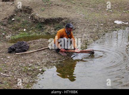 Srinagar, Inde. Mar 15, 2017. Un agriculteur du cachemire ses outils de nettoyage dans l'étang le Mercredi, Mars 15, 2017, dans la banlieue de Srinagar, dans le Cachemire sous contrôle indien. Credit : Umer Asif/Pacific Press/Alamy Live News Banque D'Images