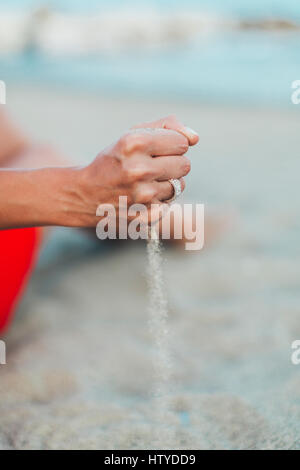 Le sable qui traverse un woman's hands Banque D'Images