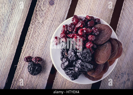 Les fruits secs sur la plaque blanche sur la surface en bois. Voir l'Flatlay Banque D'Images
