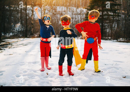 Trois enfants debout sur lac gelé wearing superhero costumes Banque D'Images