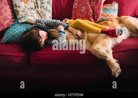 Girl sleeping on couch with golden retriever dog Banque D'Images