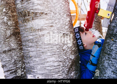 Boy in tree house looking through telescope Banque D'Images