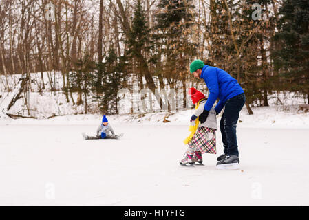 Père et deux enfants du patin à glace sur un lac Banque D'Images