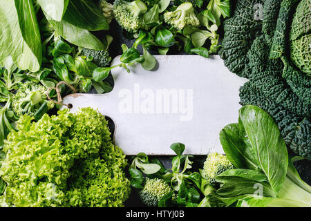 Variété de légumes verts crus des salades, la laitue, le bok choy, maïs, brocoli, chou de Milan comme cadre blanc vide ronde planche à hacher. Arrière-plan de l'alimentation. T Banque D'Images