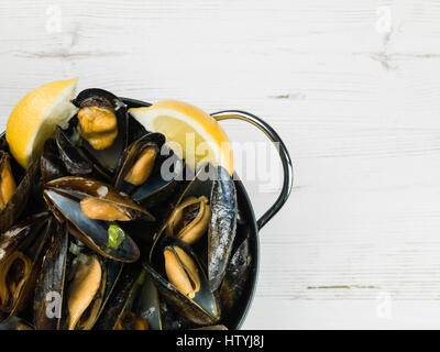 Les moules cultivées de corde dans une sauce à l'ail et l'échalote avec des tranches de citron Banque D'Images