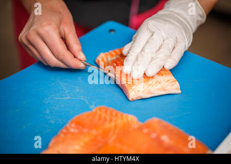 Chef, c'est la dépose de l'os de poissons saumon. Banque D'Images