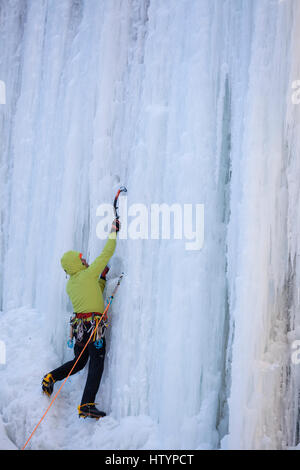 Un grimpeur sur glace escalade la frozen Buttermilk Falls à Hamilton, Ontario, Canada. Banque D'Images