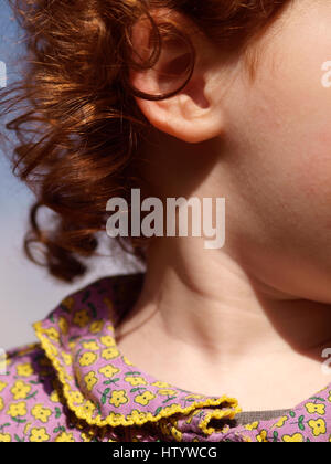 Close up de la chevelure et du visage d'un enfant de race blanche fille aux cheveux roux bouclés et un chemisier fleuri Banque D'Images