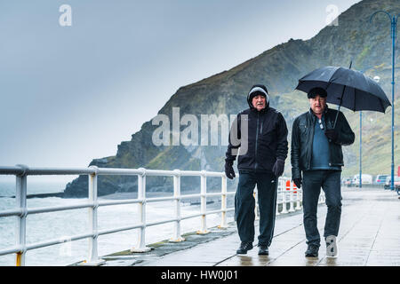 Aberystwyth, Pays de Galles, Royaume-Uni. 16 mars 2017. Après le soleil de la veille, le temps a tourné et humide à Aberystwyth, gris avec des gens s'abritant sous leur parapluie comme ils marchent le long de la promenade maintenant déserte le matin. Plus d'instabilité avec certains des forts vents sont prévues dans les jours à venir, comme la queue du verglas Stella fait son chemin à travers l'Atlantique Crédit photo : Keith morris/Alamy Live News Banque D'Images