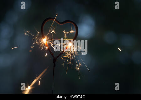 Forme de coeur sparkler brûler dans le noir Banque D'Images