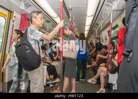 Les passagers à l'intérieur d'un wagon de métro MTR, Hong Kong, Chine. Banque D'Images