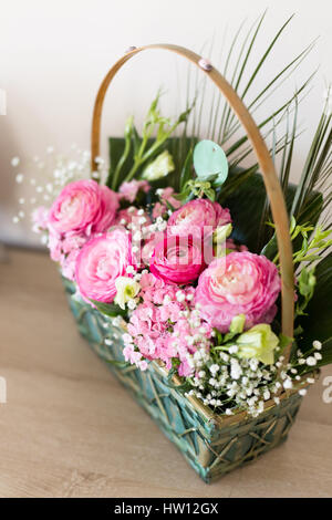 Arrangement floral dans panier avec dark and light pink ranunculus et austeria Vue de dessus avec les fleurs dans l'accent et d'autres fleurs floues Banque D'Images