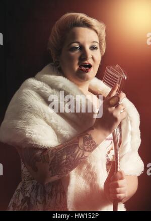 Femme en vêtements vintage retro singing into microphone dans un club Banque D'Images