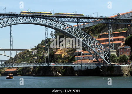 Un bateau passe sous le Pont Dom Luis I sur le fleuve Douro à Porto, alors qu'un tram qui les survolait. Banque D'Images