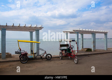 Bicitaxis typiques sont toujours en usage et servir de transport pour les habitants et les touristes. Sur la plage vide dans Cienfuegoes au coucher du soleil, Cuba Banque D'Images